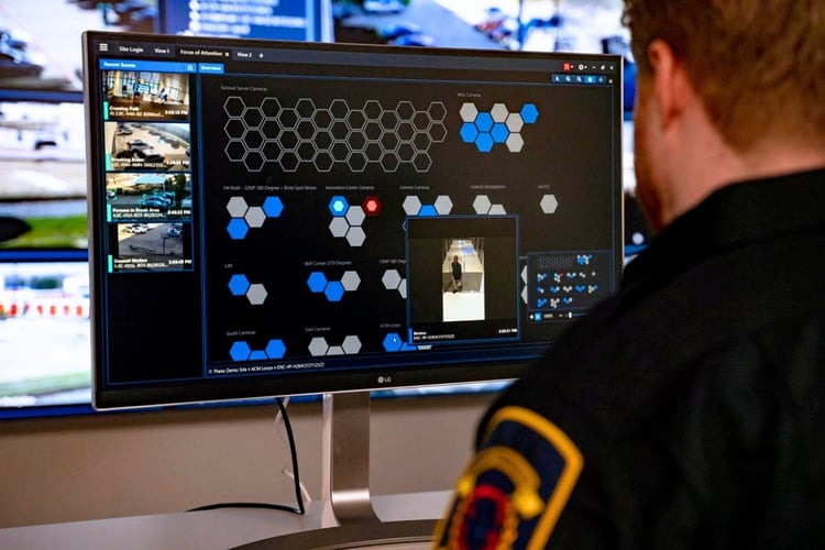 Security operator using AI video analytics software to monitor multiple surveillance feeds and detect activity in real time