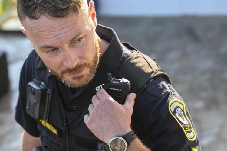 Police officer using shoulder radio for hands-free communication while staying focused on surroundings
