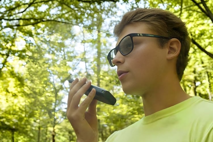 Campground staff member using a handheld radio outdoors to communicate across a wooded property