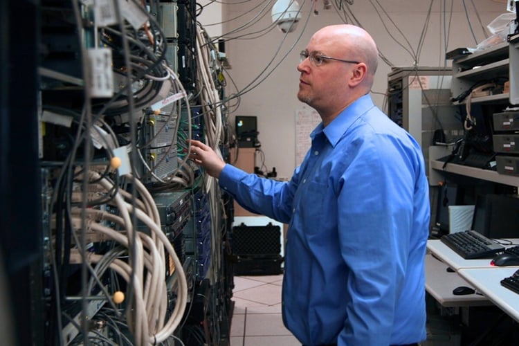 Technician inspecting communications and network infrastructure inside a data center equipment room