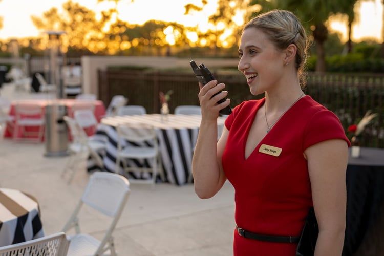 Event coordinator using a Motorola two-way radio at a large outdoor festival to manage staff communication