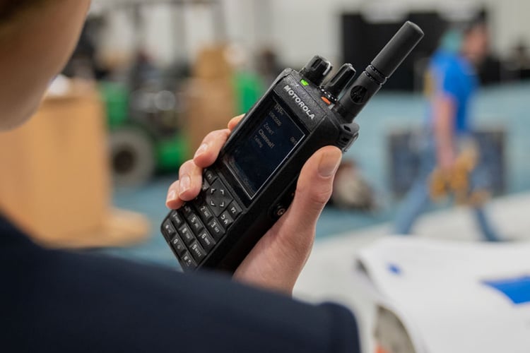 Motorola R7 two-way radio held by event staff member providing clear audio communication in a loud venue environment